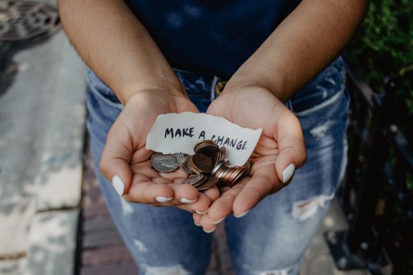 A pair of hands holding a bunch of loose change, and a scrap of paper that says "Make a Change."